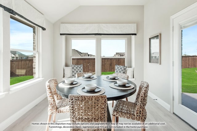 dining area featuring a healthy amount of sunlight, vaulted ceiling, and light hardwood / wood-style floors