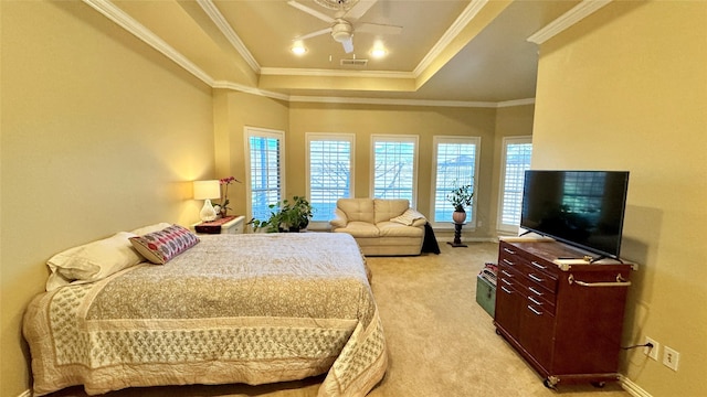 bedroom featuring ceiling fan, crown molding, light carpet, and a tray ceiling