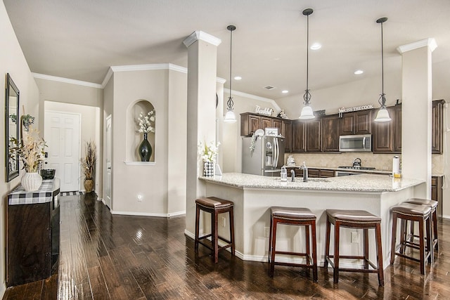 kitchen with dark brown cabinetry, sink, backsplash, pendant lighting, and appliances with stainless steel finishes