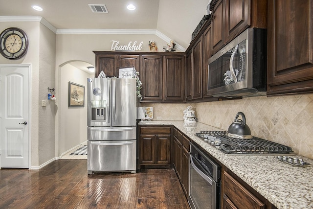 kitchen featuring light stone countertops, appliances with stainless steel finishes, tasteful backsplash, dark brown cabinets, and sink