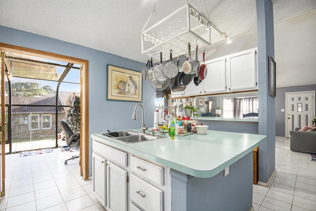 kitchen with white cabinets, a center island with sink, sink, light tile patterned floors, and a textured ceiling