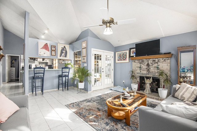 living room with ceiling fan, french doors, a brick fireplace, lofted ceiling, and light tile patterned floors