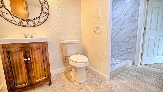 bathroom featuring vanity, a tile shower, and toilet