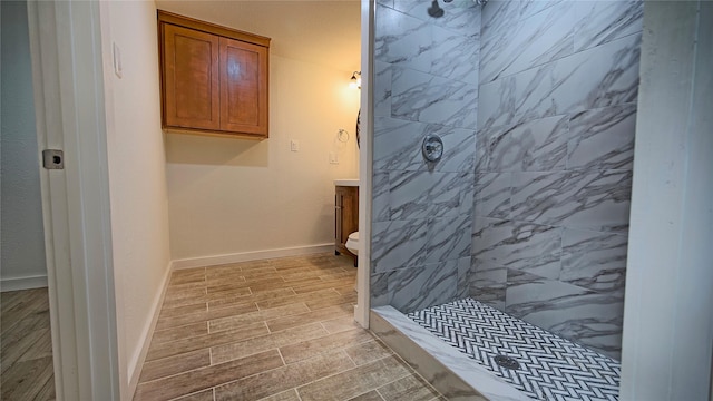 bathroom with vanity, toilet, and a tile shower