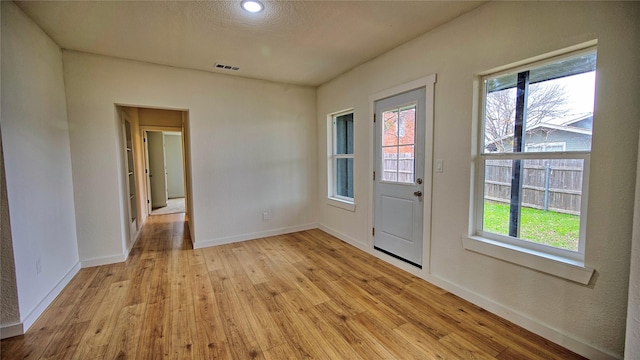 entryway with light hardwood / wood-style flooring and a textured ceiling