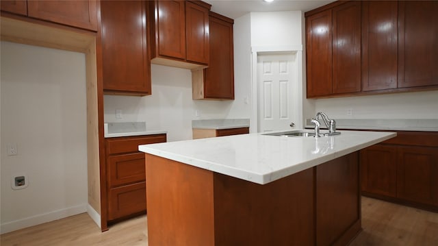 kitchen featuring sink, a kitchen island with sink, and light wood-type flooring