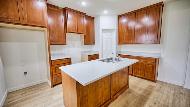 kitchen with an island with sink, sink, and light hardwood / wood-style flooring