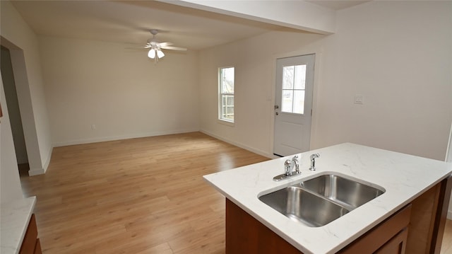 kitchen featuring a kitchen island with sink, sink, light hardwood / wood-style floors, and ceiling fan