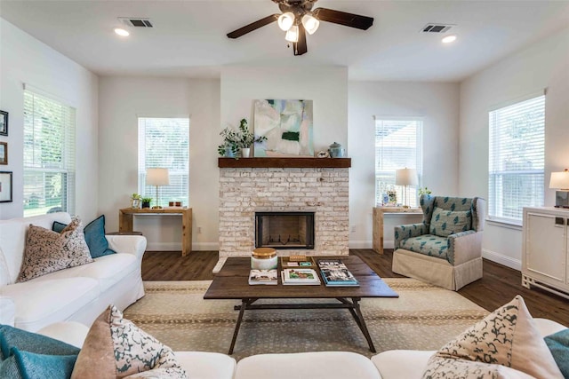 living room featuring ceiling fan, a fireplace, and dark wood-type flooring