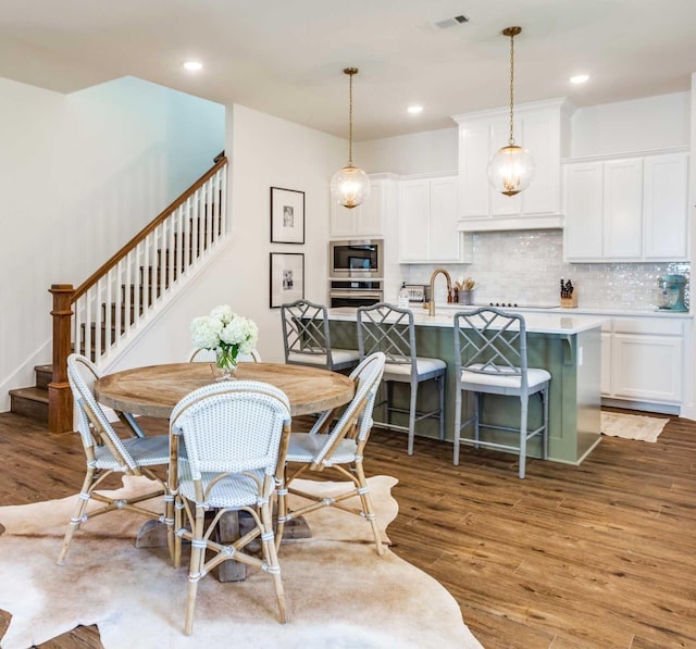 dining room with dark wood-style floors, recessed lighting, visible vents, and stairway