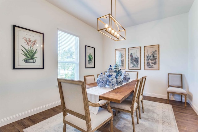 dining area featuring a chandelier, baseboards, and wood finished floors