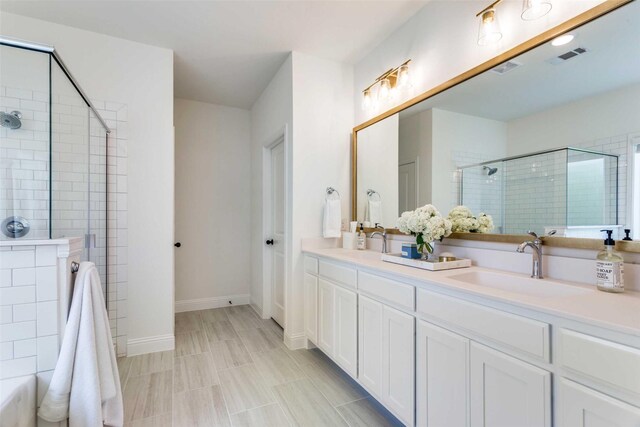 bathroom featuring visible vents, a sink, a shower stall, and double vanity