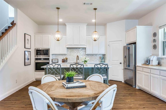 kitchen featuring stainless steel appliances, white cabinets, light countertops, and hanging light fixtures