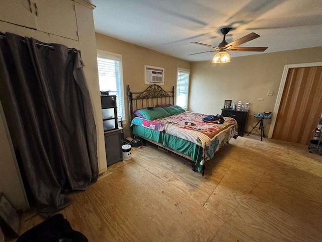 bedroom with multiple windows, a wall mounted air conditioner, and ceiling fan