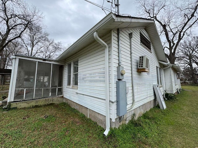 view of side of home with a wall mounted AC, a sunroom, and a lawn