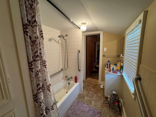 bathroom with lofted ceiling, tile walls, and shower / bath combo with shower curtain