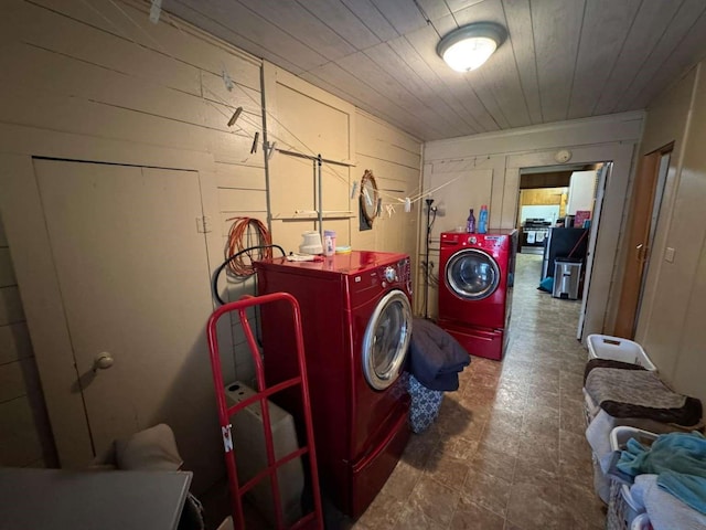 laundry area with independent washer and dryer and wood walls