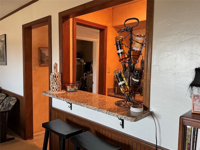 bar featuring stone counters and ornamental molding