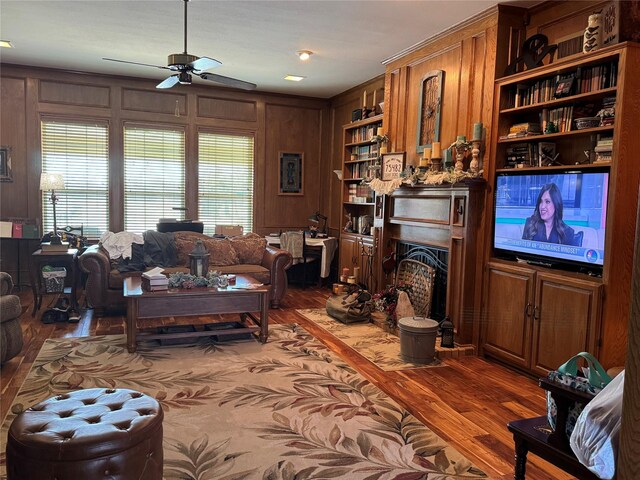 living room with ceiling fan, dark wood-type flooring, and wood walls