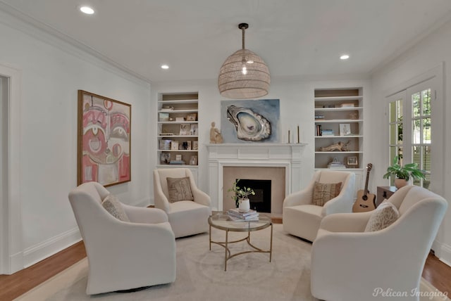 living room featuring crown molding, light hardwood / wood-style floors, and built in features