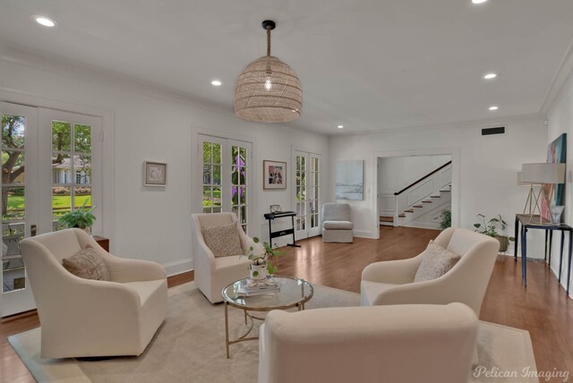 living room with french doors, ornamental molding, plenty of natural light, and light wood-type flooring