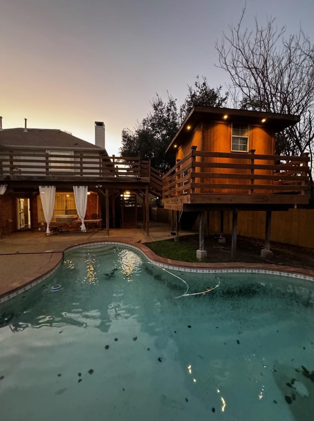 pool at dusk with a patio area and a deck