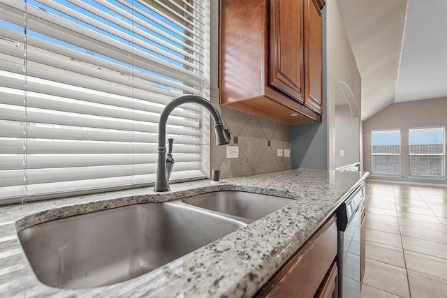 kitchen featuring light tile patterned flooring, sink, backsplash, stainless steel dishwasher, and light stone counters