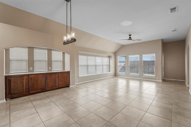 empty room with lofted ceiling, ceiling fan with notable chandelier, and light tile patterned floors