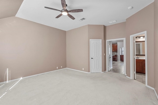 unfurnished bedroom with lofted ceiling, sink, ensuite bath, ceiling fan, and light carpet