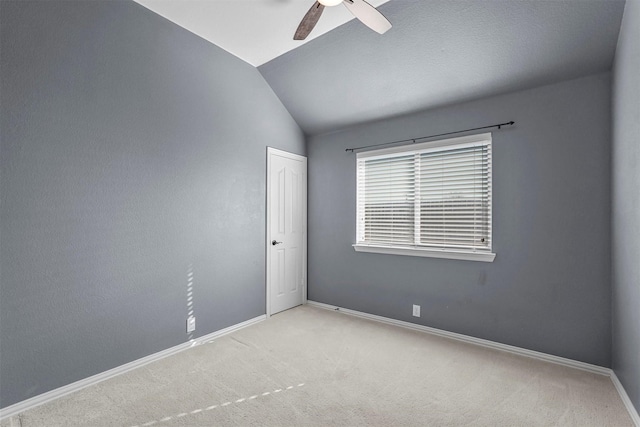 carpeted empty room featuring ceiling fan and vaulted ceiling