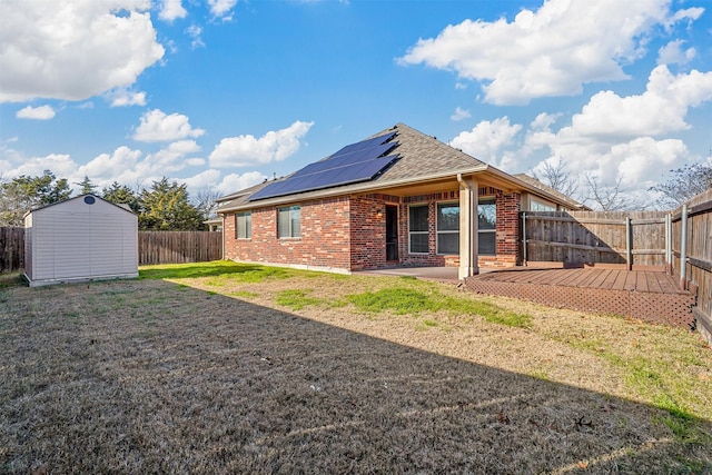 back of house featuring solar panels, a lawn, a patio area, and a shed