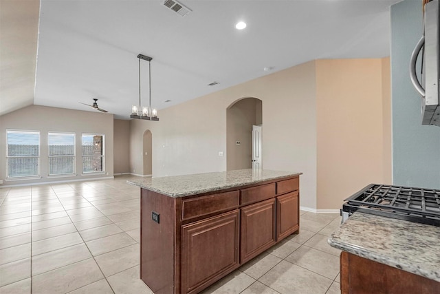 kitchen with appliances with stainless steel finishes, hanging light fixtures, a kitchen island, light stone counters, and light tile patterned flooring