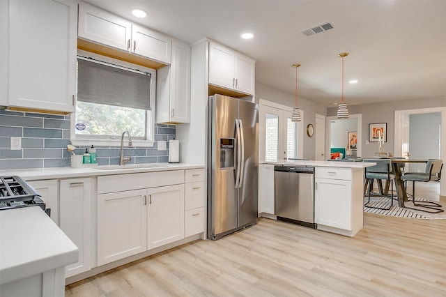 kitchen featuring white cabinetry, sink, stainless steel appliances, and decorative light fixtures