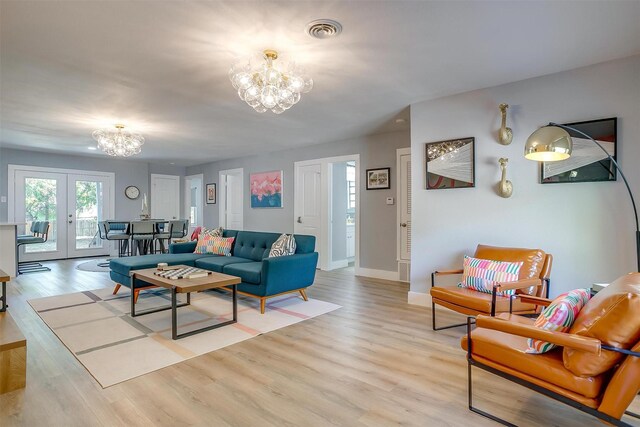 living room featuring french doors, light wood-type flooring, and an inviting chandelier