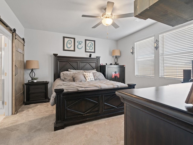 bedroom featuring ceiling fan, light carpet, and a barn door