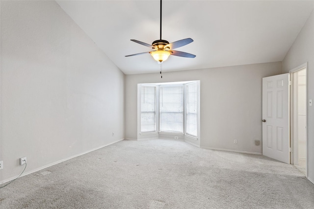 spare room with light colored carpet, vaulted ceiling, and ceiling fan