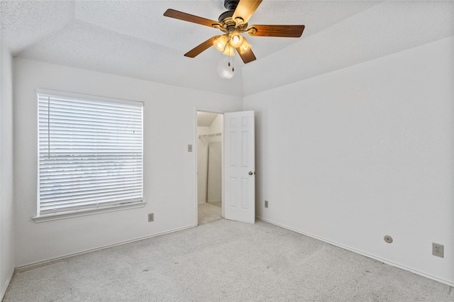 carpeted spare room with ceiling fan, lofted ceiling, and a textured ceiling