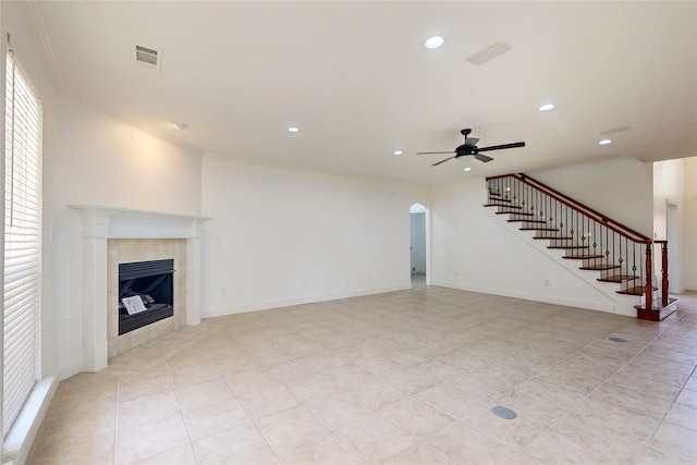 unfurnished living room featuring a tile fireplace, ornamental molding, and ceiling fan