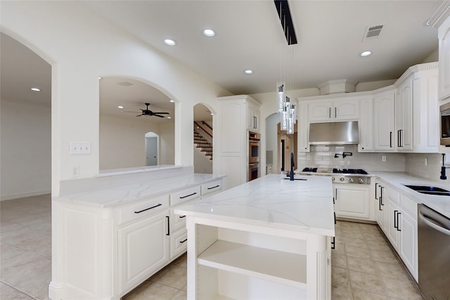 kitchen with white cabinetry, light stone counters, stainless steel appliances, and a kitchen island