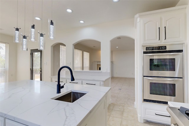 kitchen featuring pendant lighting, an island with sink, and double oven