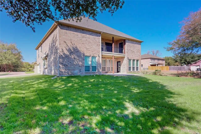 rear view of property with a yard and a balcony