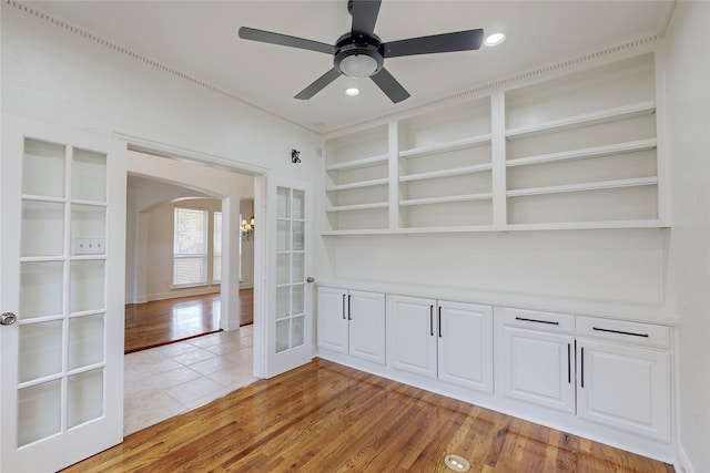 interior space featuring ceiling fan, built in shelves, light wood-type flooring, and french doors