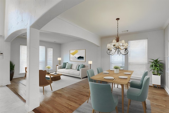 dining space featuring crown molding, a chandelier, and light hardwood / wood-style flooring