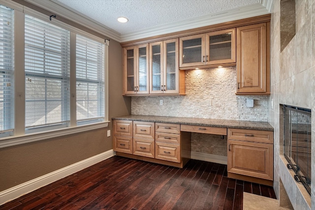 unfurnished office featuring a textured ceiling, built in desk, dark hardwood / wood-style flooring, and a healthy amount of sunlight