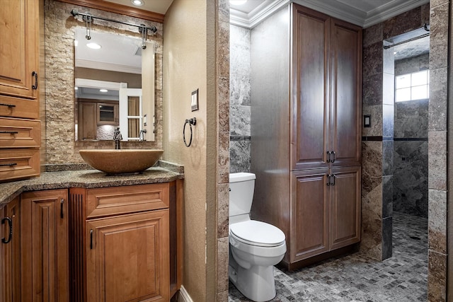 bathroom with tiled shower, toilet, vanity, and ornamental molding