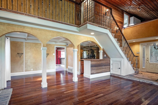 interior space featuring dark hardwood / wood-style flooring, ornate columns, coffered ceiling, crown molding, and beam ceiling