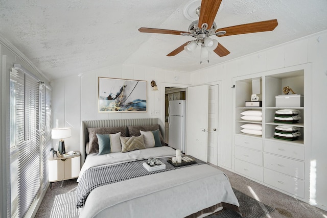 bedroom with lofted ceiling, a textured ceiling, white refrigerator, carpet floors, and ceiling fan