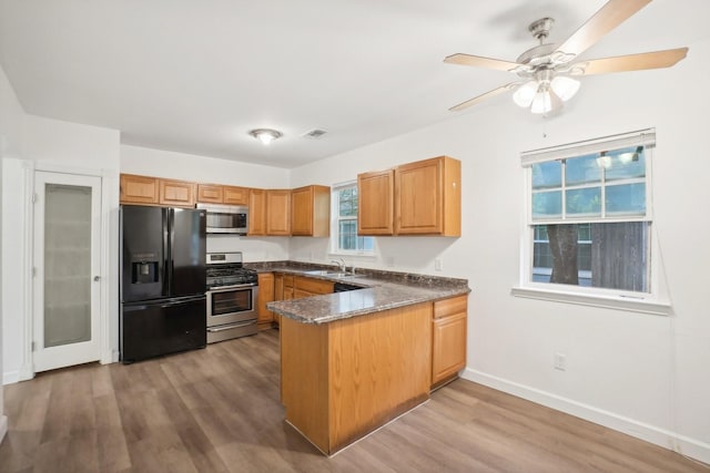 kitchen featuring stainless steel appliances, sink, light hardwood / wood-style flooring, and kitchen peninsula