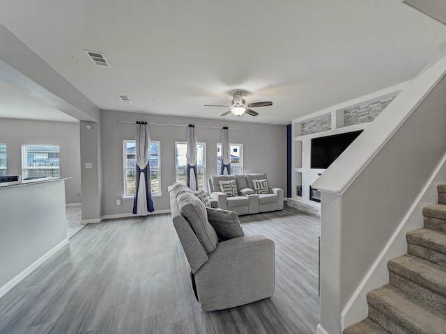 living room with wood-type flooring, built in features, and ceiling fan