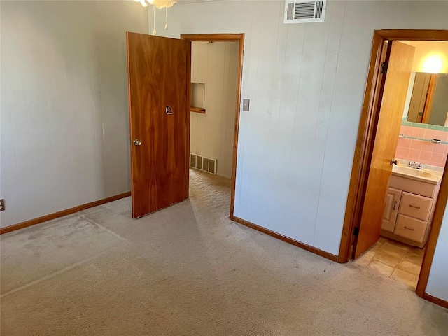 unfurnished bedroom with light colored carpet, sink, and ensuite bath